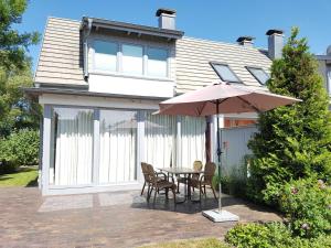 a table and chairs with an umbrella in front of a house at Exkl FH Quäkenpüker, Kamin, W-LAN in Börgerende-Rethwisch