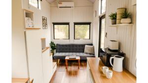 un soggiorno con divano in una casetta minuscola di Odyssean Tiny House A by Tiny Away a Cessnock