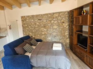 a living room with a blue couch and a stone wall at Tra Monti e Lago in Lecco