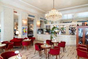a restaurant with red chairs and tables and a chandelier at Hotel Vittoria in Brescia