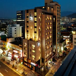 Un palazzo alto in una strada di città di notte di Urban Island Hotel Jeju a Jeju