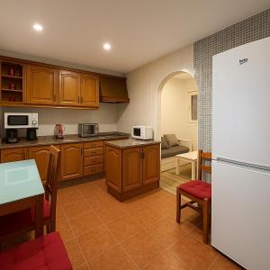 a kitchen with wooden cabinets and a white refrigerator at Apartamento en el centro de 2 hab. y 2 baños. in Castro-Urdiales