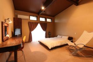 Schlafzimmer mit einem Bett, einem Schreibtisch und einem Fenster in der Unterkunft Sunny Spot in Minamitan