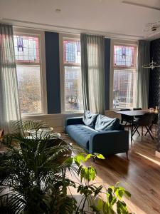 a living room with a blue couch in front of windows at Apartement City Centre with roof terrace and parking with additional costs in The Hague