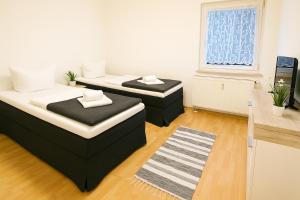 two beds in a small room with a window at SUNNYHOME Monteurwohnungen und Apartments nahe Regensburg in Nittendorf