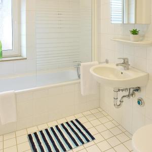 a white bathroom with a sink and a bath tub at SUNNYHOME Monteurwohnungen und Apartments nahe Regensburg in Nittendorf