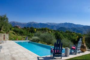 a pool with two chairs and a view of the mountains at Cà del Vento amazing villa 10 pax w/ infinity pool in Bagnone