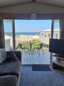 a living room with a table and chairs on a deck at Thornwick bay Yellowhammer 28 in Flamborough