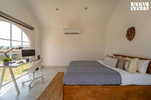 a bedroom with a bed and a desk and a window at StayVista at The Leo's Manor with Bonfire, Pool in Jaipur