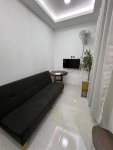 a living room with a black couch and a table at Demo Inn in Bachok