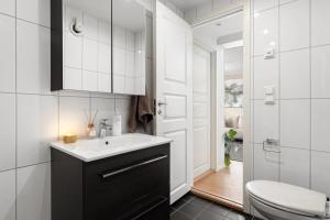 a white bathroom with a sink and a toilet at Modern 2 bedroom apartment in the heart of Tromsø in Tromsø