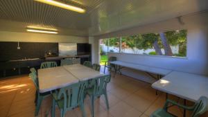 a dining room with tables and chairs and a kitchen at Bermagui Motor Inn in Bermagui