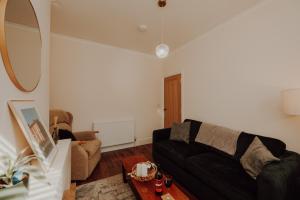 a living room with a black couch and a table at Rigg House - Ideal for Contractors 2 bed 2 bathrooms sleeps 6 free parking in Doncaster