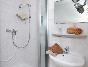 a white bathroom with a shower and a sink at Bauerncafé Sprengel in Bad Gandersheim