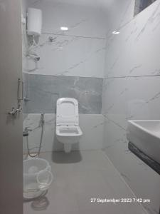 a white bathroom with a toilet and a sink at Hotel Kingdom in Gandhinagar