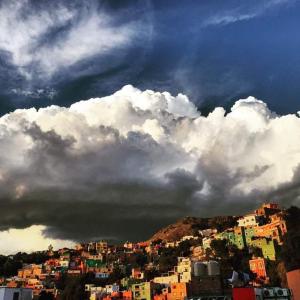 um grupo de edifícios em uma colina sob um céu nublado em Hospedaje Del Campanero 19 em Guanajuato
