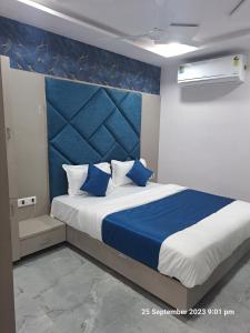 a bedroom with a large bed with a blue headboard at Hotel Kingdom in Gandhinagar +16 photos