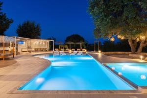 a swimming pool at night with chairs around it at Hamilton Grand Villa in Koskinou