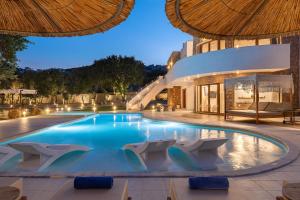 a large swimming pool with chairs and a building at Hamilton Grand Villa in Koskinou