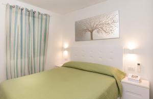 ein Schlafzimmer mit einem grünen Bett und einem Baum an der Wand in der Unterkunft Villetta Otis by Wonderful Italy in San Teodoro
