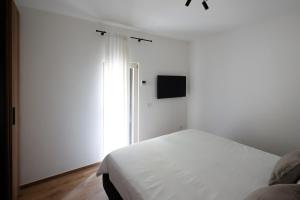 ein weißes Schlafzimmer mit einem Bett und einem Fernseher in der Unterkunft Podere Sabaina, Private Villa mit Pool, Seeblick und 3 Wohneinheiten zur Alleinnutzung in Torri del Benaco