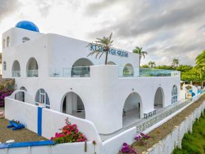 Un edificio blanco con flores delante. en Grecialandia, en San Felipe de Puerto Plata