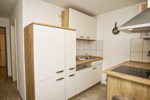 une cuisine avec des armoires blanches et un évier dans l'établissement FeWo am Hochzeitsberg FeWo 17 - Souterrain, à Breege