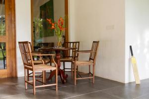 einen Holztisch mit Stühlen und eine Vase mit Blumen in der Unterkunft Boundary House in Galle