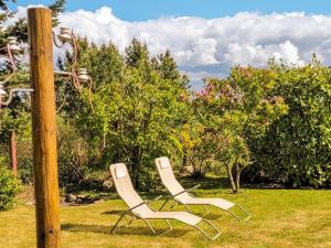 two white chairs sitting next to a wooden pole at Ferienwohnung Lüssow in Lüssow