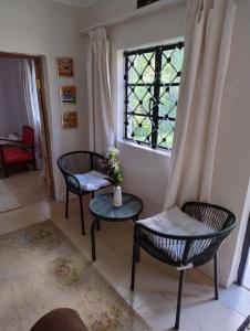 a room with two chairs and a table and a window at Zambarau house in Busia