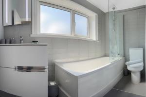 a white bathroom with a tub and a toilet at London 5 BR 3 Bathroom Garden Hse Near Metro and Hampstead Heath Sleeps 10 in London +49 photos