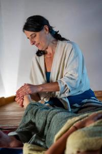 a woman sitting on a bed with a towel on her leg at Las Lucías, experiencias de ecoturismo in Navatrasierra