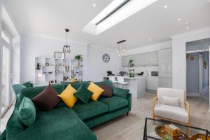 a living room with a green couch and a kitchen at London 5 BR 3 Bathroom Garden Hse Near Metro and Hampstead Heath Sleeps 10 in London