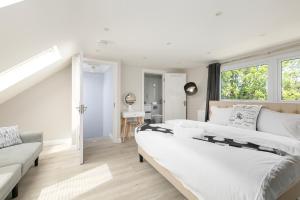 a white bedroom with a large bed and a window at London 5 BR 3 Bathroom Garden Hse Near Metro and Hampstead Heath Sleeps 10 in London