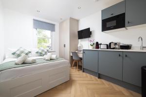a white bedroom with a kitchen and a bed at Charmstay Kensington Olympia in London
