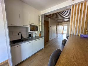 a kitchen with white cabinets and a long table at Harem House in Mielno