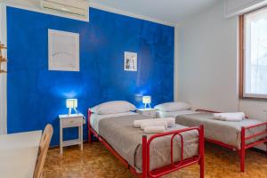 two beds in a room with a blue wall at Lecco Adventure Base in Lecco