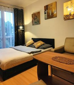 a room with two beds and a couch and a table at Apartament TwojaNoc in Mielec
