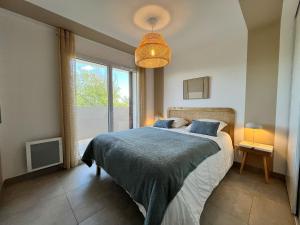 Un dormitorio con una cama y una ventana grande. en NAÏA Nig, en Sérignan