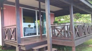 a porch of a red house with a wooden deck at Pension de famille HITI MOANA VILLA in Papara