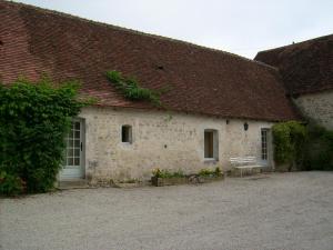 un edificio in pietra con una panchina di fronte di Chambre d'hôte au domaine de la Miottiere a Le Pin-la-Garenne