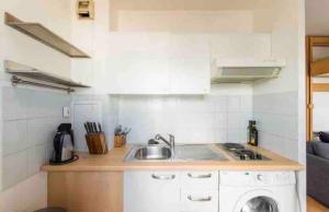 a kitchen with a sink and a washing machine at Petit paradis in Clichy