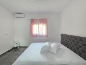 Un dormitorio con una gran cama blanca con ventana. en Gavriel's house Eretria, en Eretria