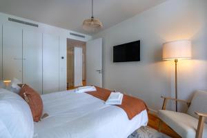 Un dormitorio con una cama y una silla y un televisor. en Cond Bayline - Pool - Gyn - SPA - Peixe Balão - BY BEDZY, en Armação de Pêra