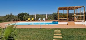a swimming pool with chairs and a gazebo at Monte Malk Abran in Vila de Frades
