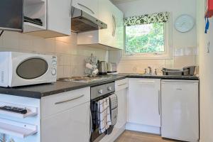 a kitchen with white cabinets and a microwave at Finest Retreats - Lanteglos Villa in Camelford