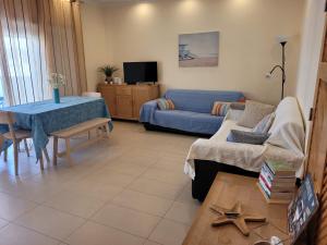 a living room with a blue couch and a table at A Cabaninha - T2 Cabanas Beach in Tavira