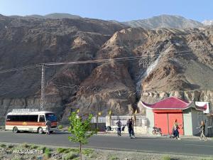 a bus parked on the side of a street with mountains at Dream Palace Hotel Rakaposhi Nagar in Gilgit