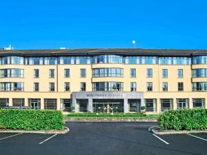 a large building with a parking lot in front of it at Family Friendly Mullingar Self Catering Apartment on Park Hotel Grounds in Mullingar