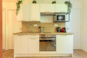 kuchnia z białymi szafkami i mikrofalówką w obiekcie Lille Sébastopol nice studio w Lille
